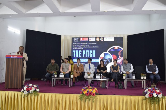 Wide view of the stage with the speaker at the podium and panel seated